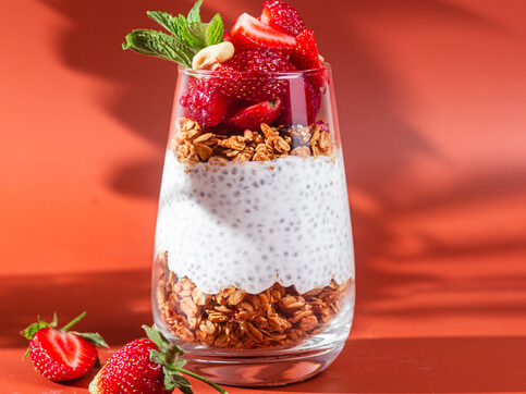 Granola with yogurt, chia and strawberries in a glass on a bright background